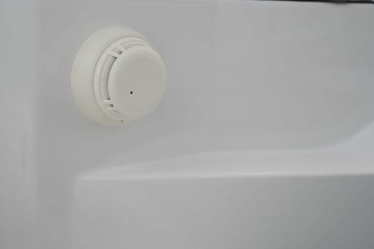 A smoke detector is mounted on the bathroom wall for fire safety.