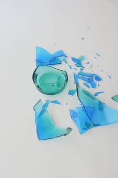 Bright turquoise glass pieces are scattered across a white surface.