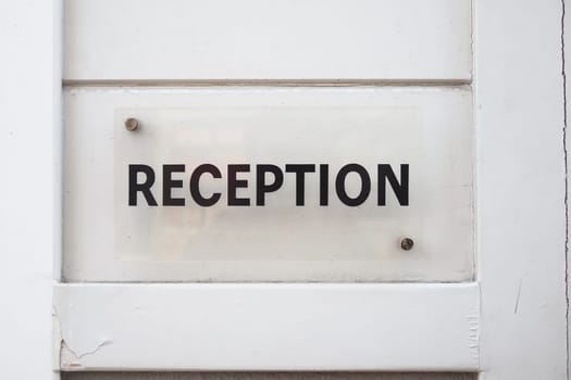 A clear sign indicating reception area located near an entryway.