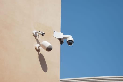 Security cameras observe the area from a building's corner during daytime.