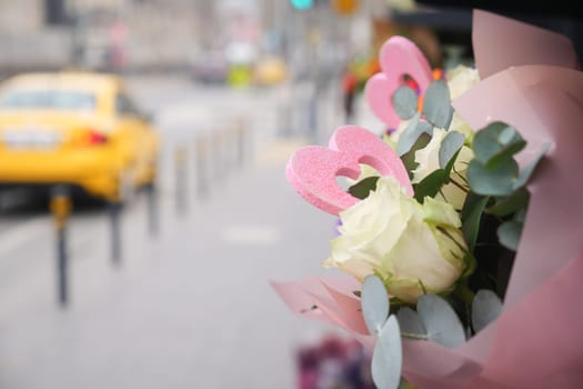 Colorful flowers with heart shapes are displayed on a city sidewalk.