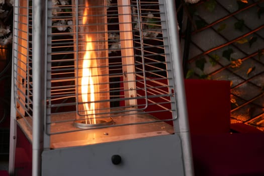 Warm flames flicker in an outdoor heater surrounded by decorations.