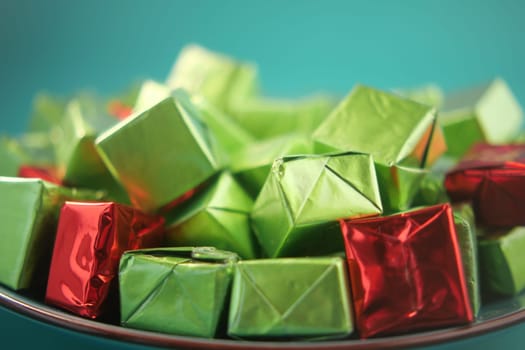 Brightly wrapped green and red gifts displayed on a plate inviting celebration.