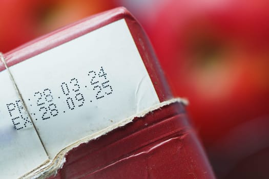 Close-up of red packaging displaying production and expiry dates in a store.