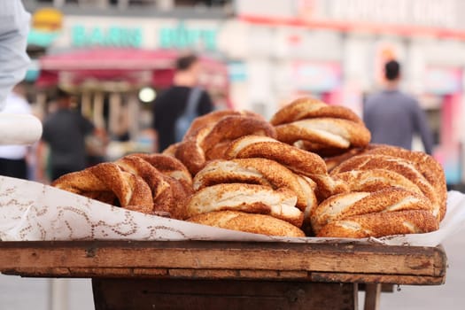 Warm, freshly baked simit rolls are arranged on a wooden cart in a market.