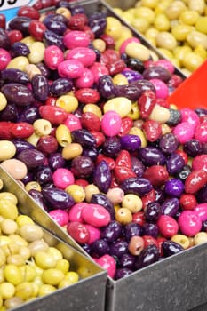 Vibrant selection of olives in various colors arranged in baskets at market.