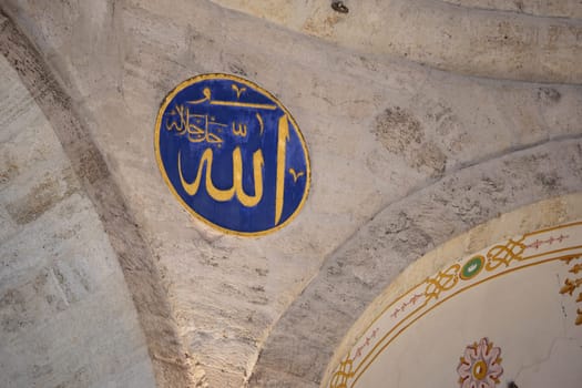 Beautiful blue calligraphy of Allah adorns a stone archway inside the mosque.