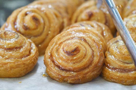 Warm, golden cinnamon rolls with a glossy finish sit on display.
