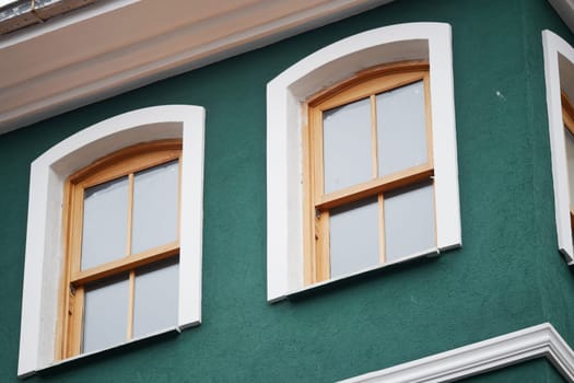 Two wooden windows are framed in white, set against a green wall.