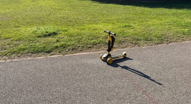 Budva,Montenegro-April 11,2025:Close-up of yellow children's scooter on park path. High quality photo