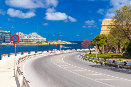 Empty coastal road around the walled town of Valletta, Malta. The town of Sliema in the background.