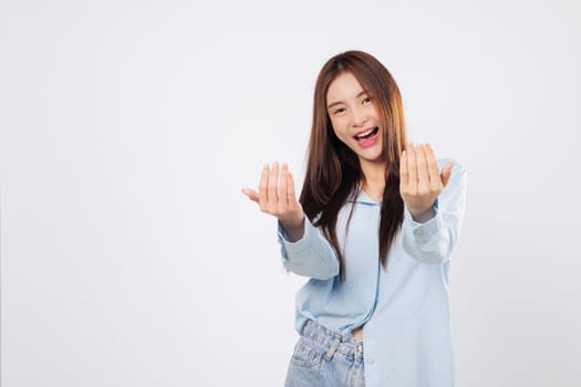 Woman uses hand gesture to beckon come here, while another woman stands with palm extended in a welcoming pose, cheerful expressions isolated in white studio background.