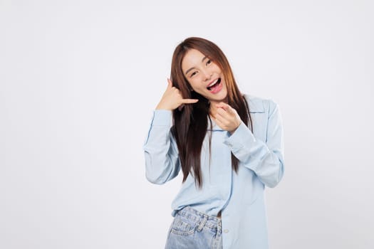 Woman gestures call me sign with hand by her ear, another woman mimics phone using fingers and pointing finger, both cheerful and expressive in front isolated of white background.