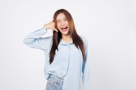 Woman making call me gesture with fingers, another woman smiles winking while mimicking a phone with hand near face, playful studio pose isolated on white background.