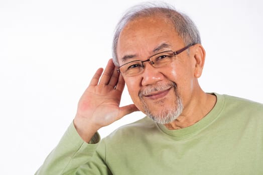 Portrait Asian old man with glasses and a beard listening to sound something, possibly engaged in conversation or trying to understand a message, hand on ear hearing a rumor isolated white background