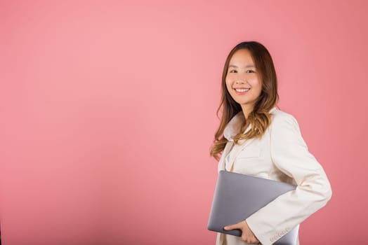Business woman smiling confident smiling holding closed laptop, Portrait excited happy Asian young female person hugging close cover computer device studio shot isolated on pink background