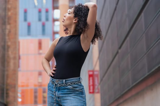 African American woman dancing in a creative pose between benches in an urban setting. She wears casual clothes and shows balance, strength, and expression. Concept of movement, art, and freedom.