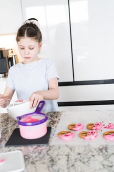 With focused attention, this budding culinary artist dips pretzels into a pot of melted chocolate, creating sweet delights in the warmth of a well-lit home kitchen.
