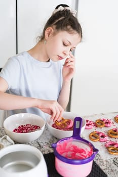 With focused attention, this budding culinary artist dips pretzels into a pot of melted chocolate, creating sweet delights in the warmth of a well-lit home kitchen.