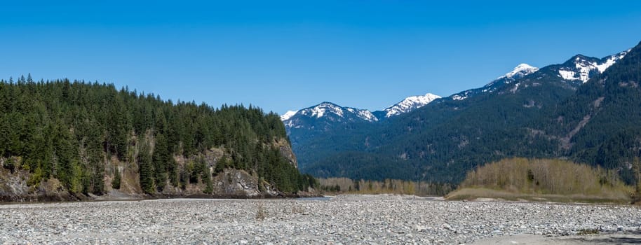 Panoramic view of Rocky mountains in British Columbia. Stoney riverbed in the mountains