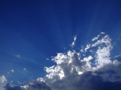 Blue sky with fluffy white clouds creating a shadow, Bright sunshine, purity and tranquility of boundless space.