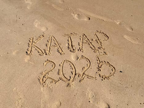 An inscription on a clean yellow sand beach in Doha, Qatar, 2025