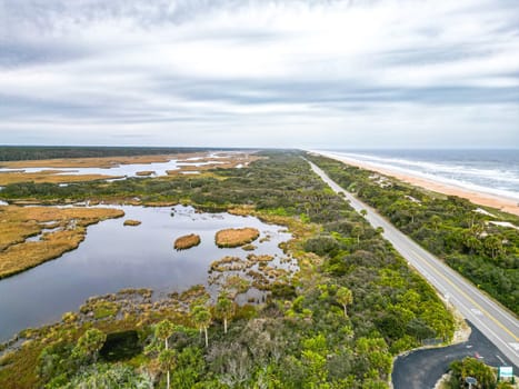 This beautiful stock image showcases a scenic Florida highway, flanked by lush wetlands on one side and the sparkling Atlantic Ocean on the other, emphasizing the region s stunning natural beauty.