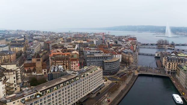 Geneve, Switzerland 04.11.2025 High-angle drone photo of a European city center with historic buildings, busy streets, a hotel, bridges, and a lake fountain view.