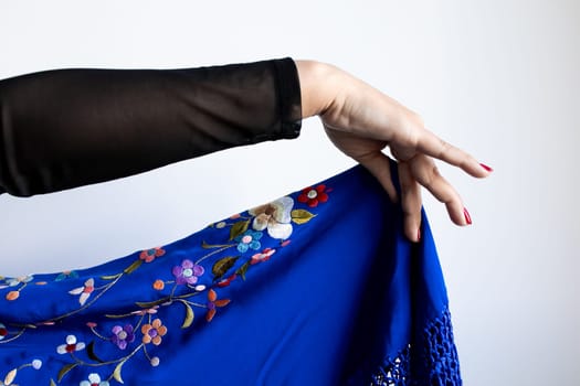 Elegant display of woman hand with blue floral embroidered fabric.