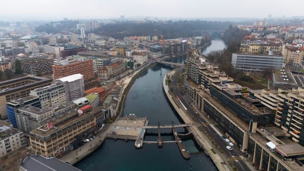 High-angle aerial shot of Geneva riverbanks, bridges, and urban buildings, highlighting city planning and architecture on a cloudy day. Geneve, Switzerland 04.11.2025