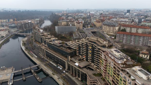 A drone shot of showcasing brutalist buildings, a river, and cityscape under cloudy skies. Ideal for urban planning themes. Geneve, Switzerland 04.11.2025