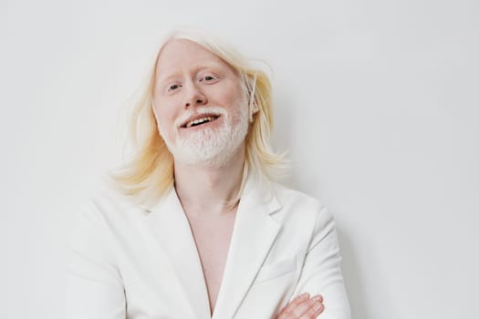 A cheerful man with long white hair and a beard wears a stylish white suit, standing confidently with crossed arms The soft, neutral background enhances the subject s vibrant personality, creating a calming, modern aesthetic