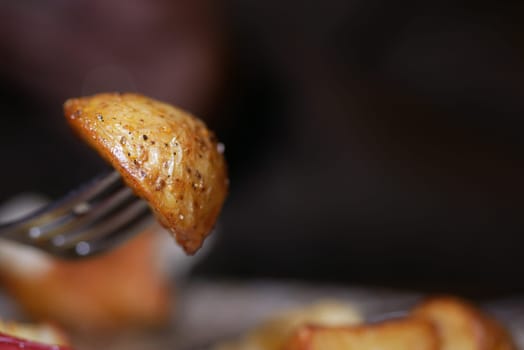 A fork holds a golden roasted potato slice, showcasing its crispy texture.
