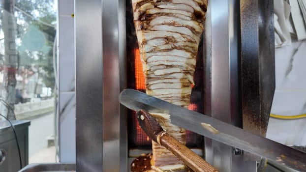 A chef skillfully slices shawarma meat at a bustling food stall.