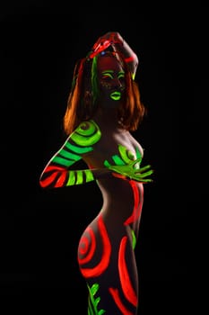 Portrait of topless woman with UV bodyart dance in dark