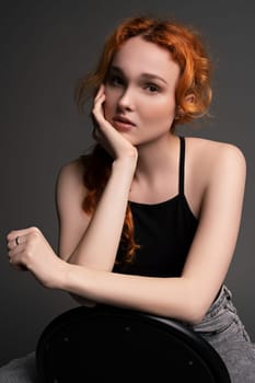Cheerful redhead female model with ginger hair in casual outfits sitting on chair with sad emotion look at camera