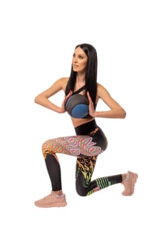 Full body side view of young fit female in sportswear and headphones stretching arms and looking at camera against white background