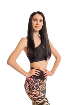 Side view of confident young female in trendy outfit looking at camera with hand on waist against white background