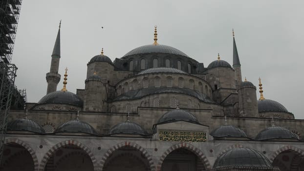 Overcast day view of the Sultan Ahmed Mosque (Blue Mosque) in Istanbul, showcasing its numerous domes, minarets, and stone facade.