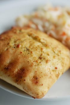 Tasty baked item with a crispy texture served alongside fresh coleslaw.