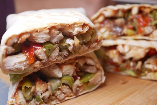 Succulent pieces of chicken and fresh vegetables are wrapped in a tortilla.