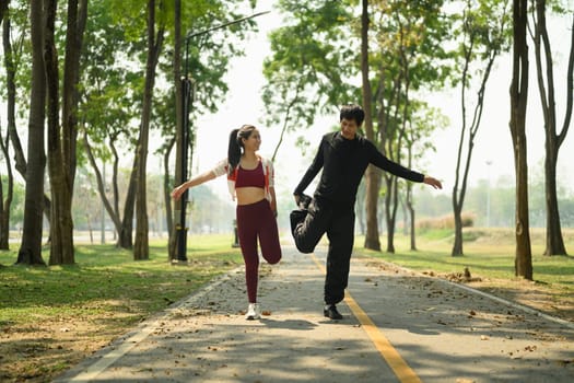 Active young couple stretching before workout in the park.