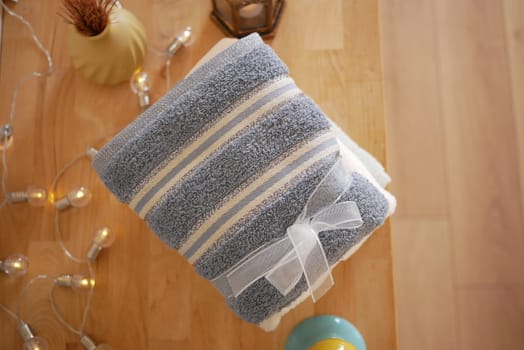 Two neatly folded towels tied with a ribbon sit on a wooden table.