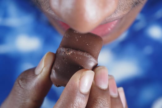 Close-up of a person savoring a delicious piece of chocolate.