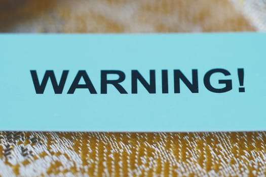 A bright warning sign contrasts with a textured background, alerting viewers.