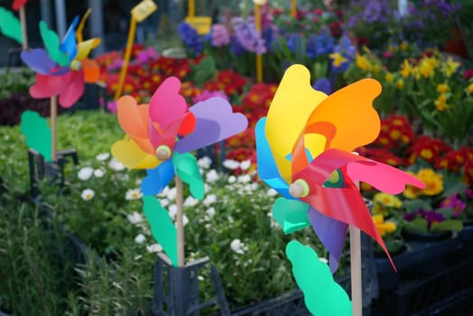 Bright pinwheels spin amidst an array of blooming flowers in springtime.