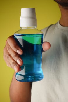 hand holding a mouth wash liquid container .