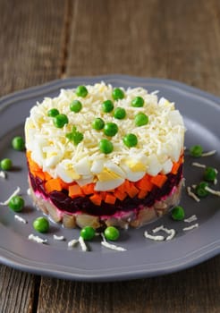 A vibrant layered salad showcasing bright elements like carrots, beets, and eggs, garnished with fresh peas, served on a gray plate. Perfect for festive occasions or gatherings.