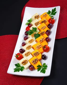 A vibrant platter displays an assortment of cheeses, walnuts, grape clusters, and cherry tomatoes. Fresh parsley adds a touch of greenery, making it an inviting centerpiece for a social event.