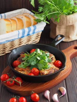 A cast iron skillet holds a vibrant dish featuring fish fillets topped with cherry tomatoes and fresh cilantro.